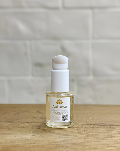 Shampoing Le Bourgeon 15 ml posé sur plan de travail en bois, soin purifiant pour cheveux naturels.