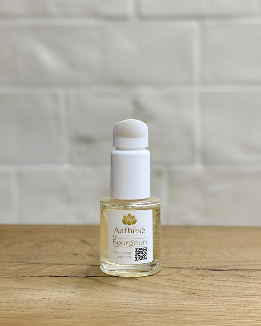 Shampoing Le Bourgeon 15 ml posé sur plan de travail en bois, soin purifiant pour cheveux naturels.